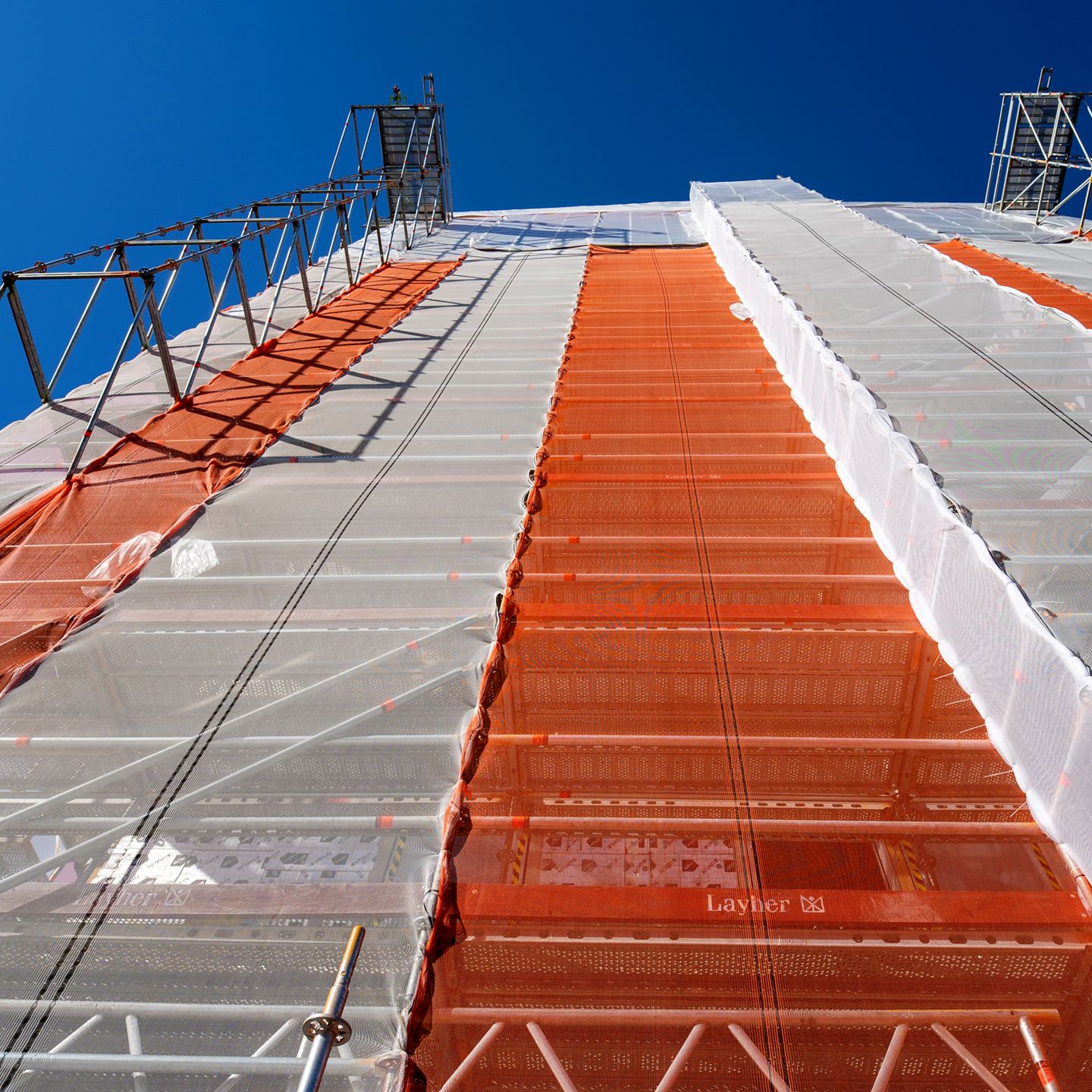 Väderskyddets tak och ställning sedd underifrån, med orange och genomskinliga takpaneler mot blå himmel